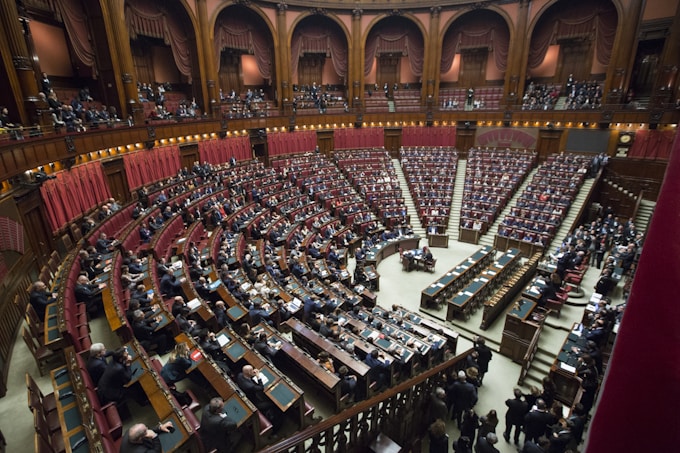 Large assembly in ornate hall, symbolizing political awareness and engagement for international 