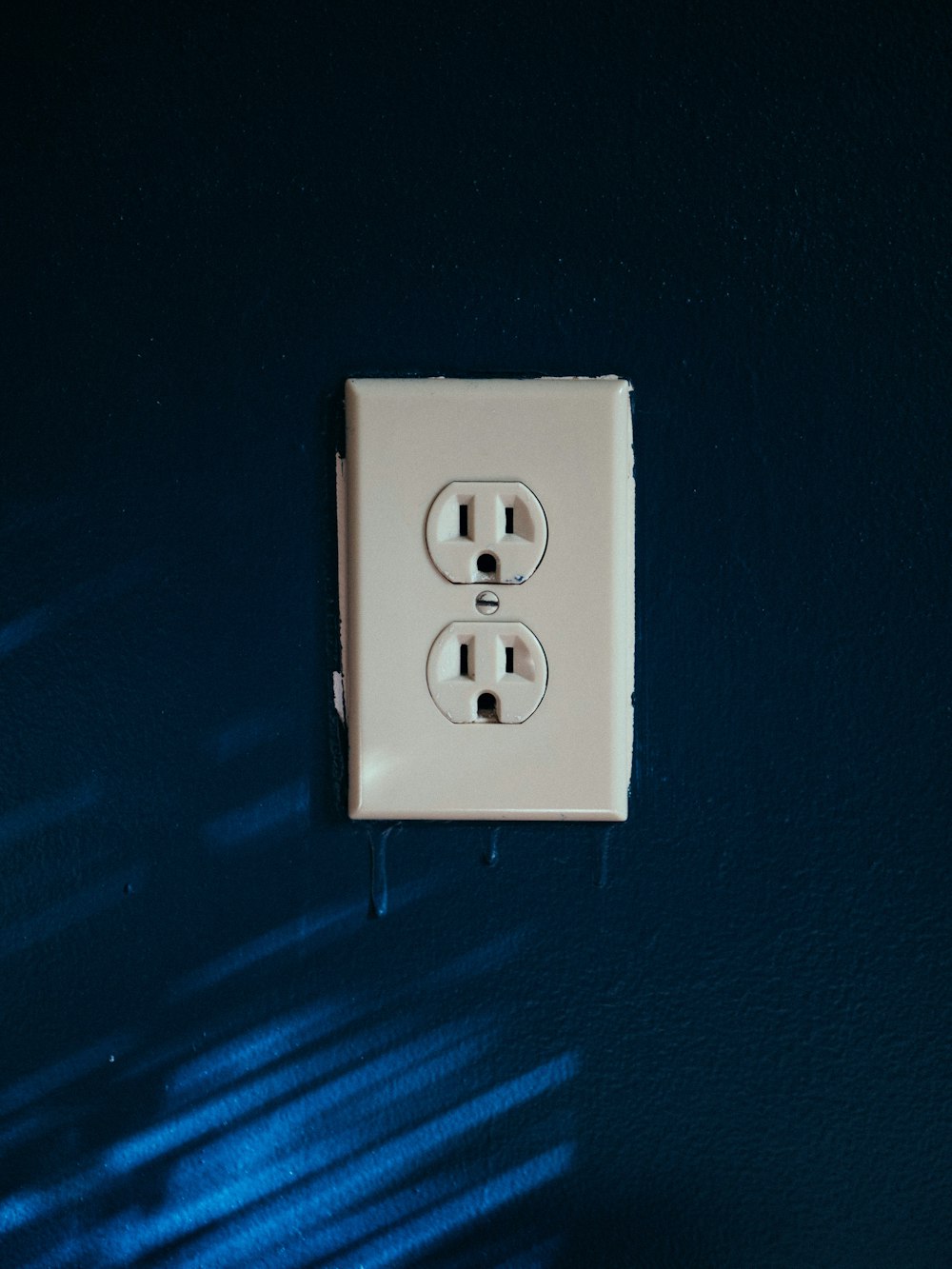 white 2-slot plug mounted on blue wall