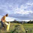 Portrait of a smiling farmer holding a sack of organic compost in a lush green field.