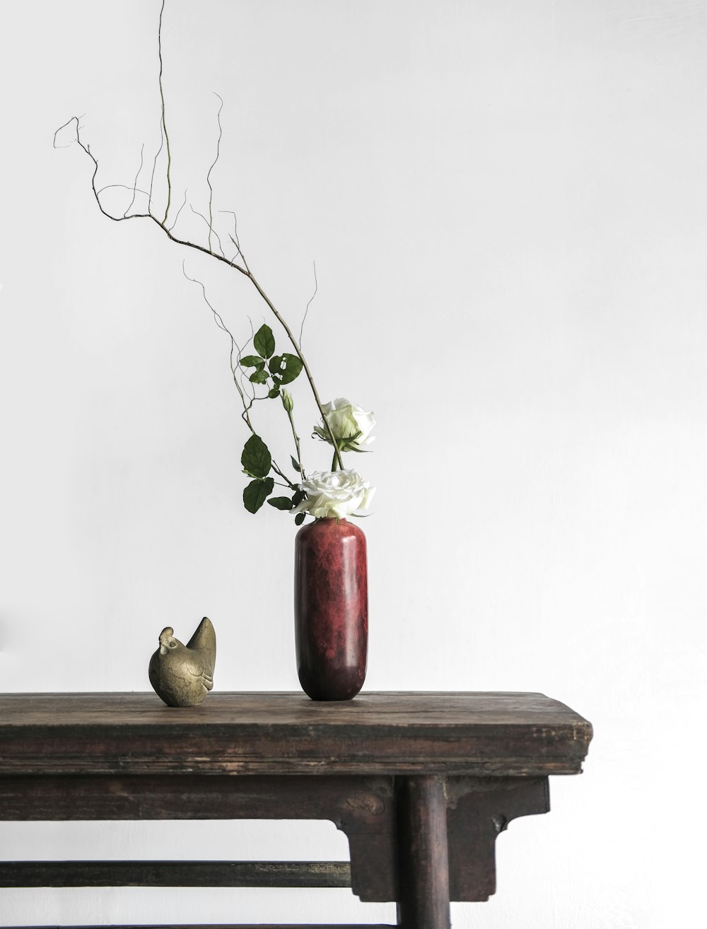 white roses in red ceramic vase