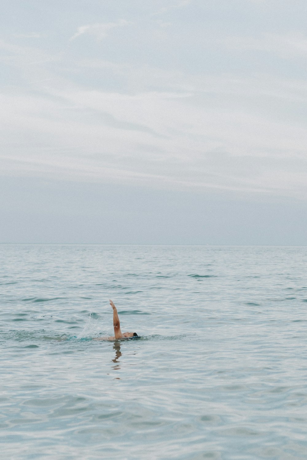 person swimming on body of water during daytime