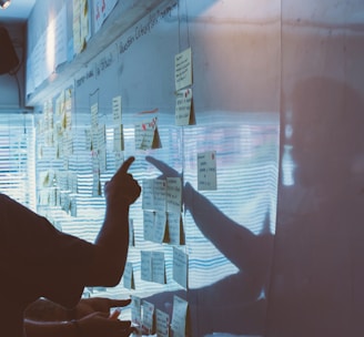 person pointing white paper on wall