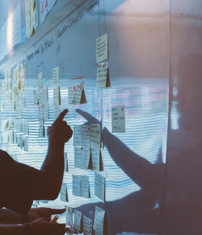 person pointing white paper on wall