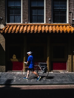 man walking while holding road bike