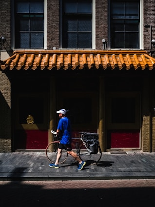 man walking while holding road bike