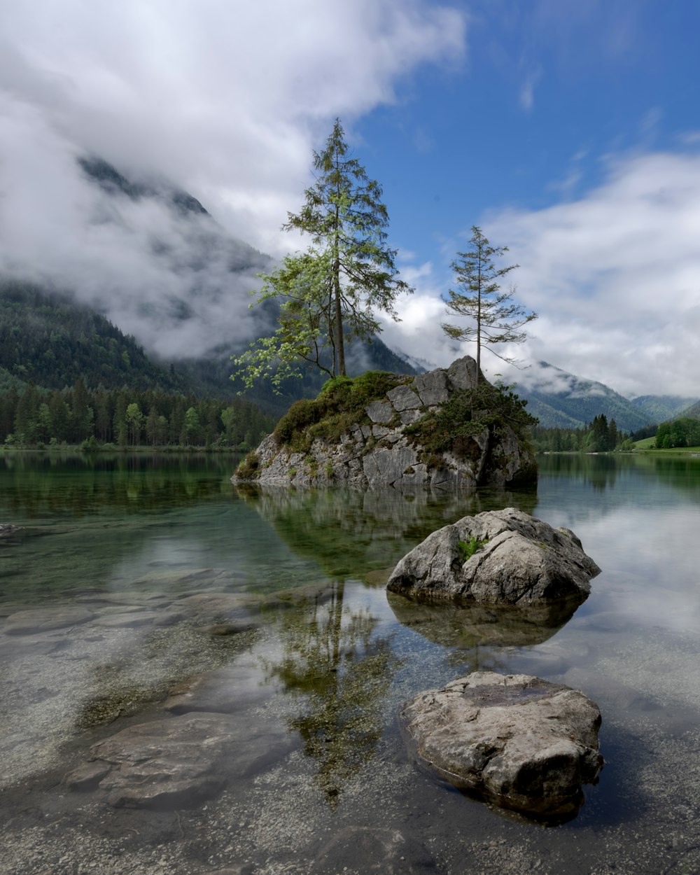 three large gray rocks surrounded by water