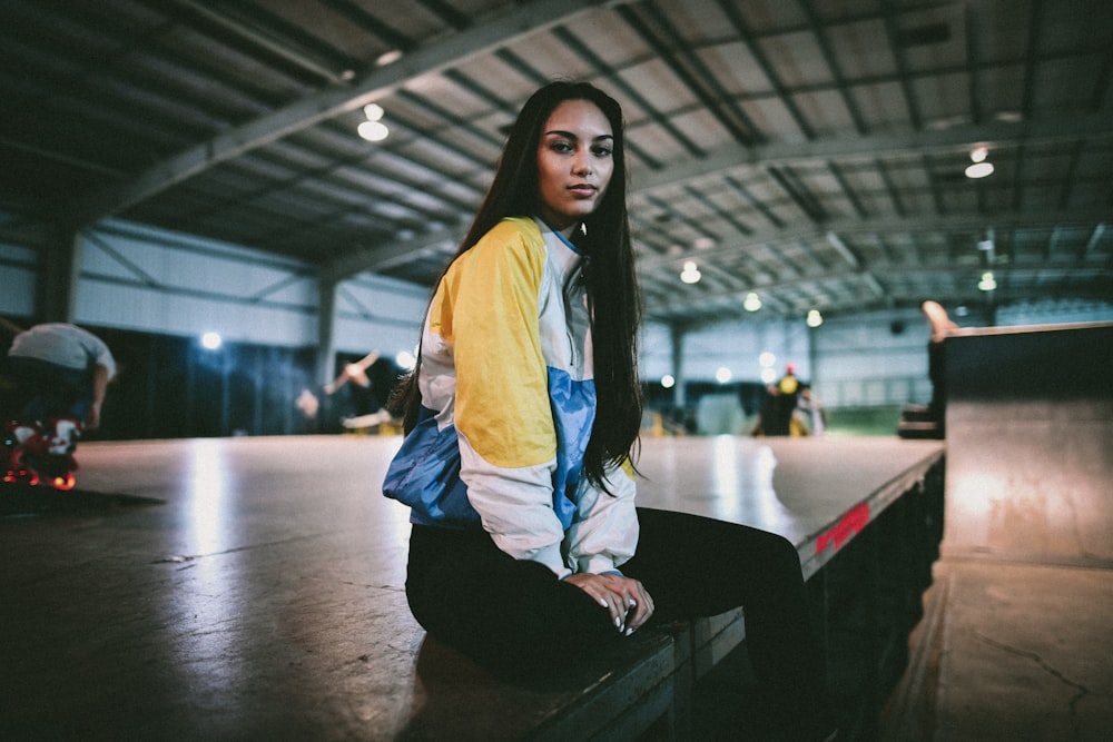 sitting woman wearing yellow, white, and black jacket