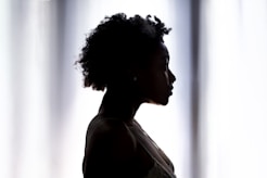 silhouette photo of woman standing near white cloth