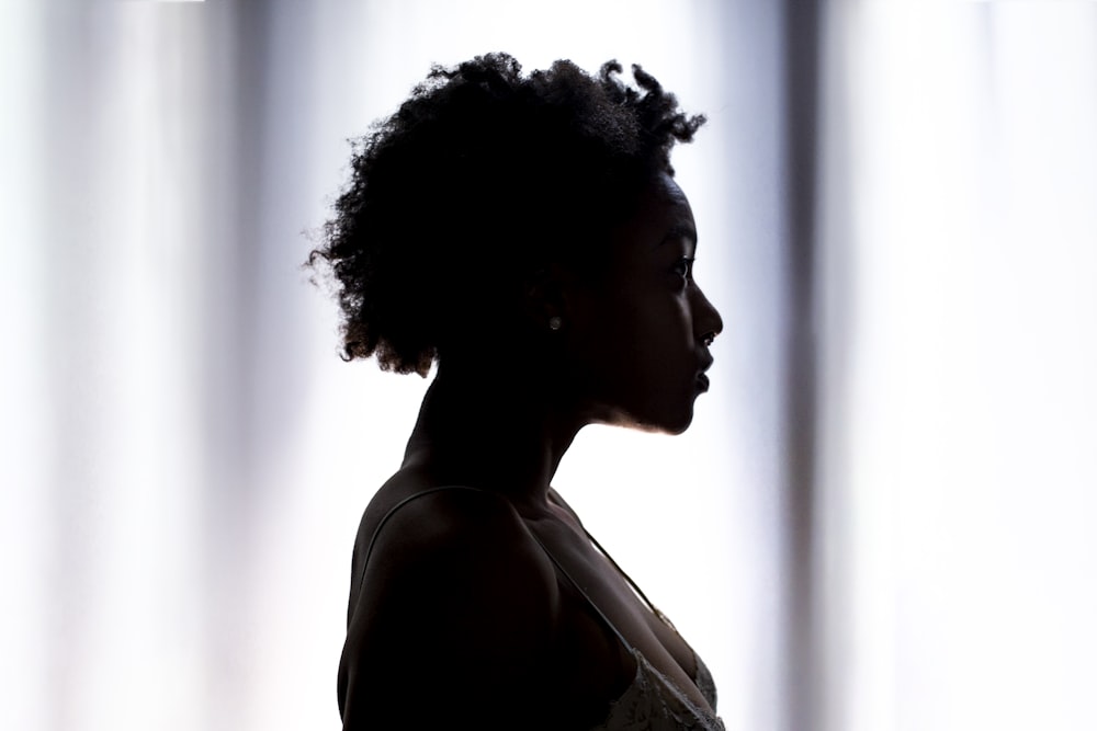 silhouette photo of woman standing near white cloth