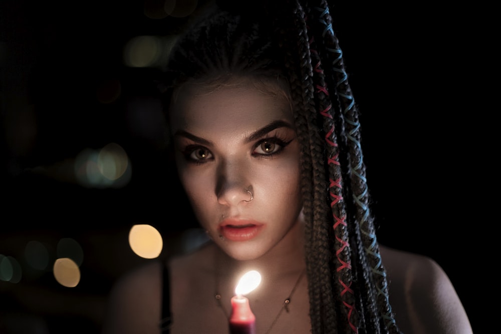 red lighted candle near woman's face close-up photography