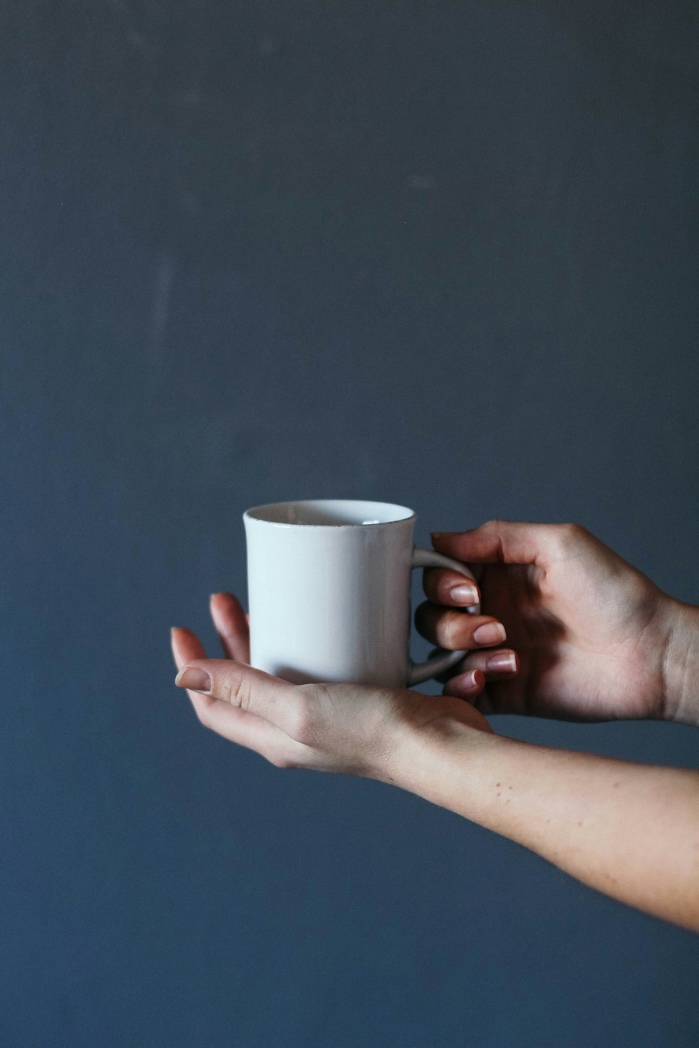 Persona che tiene la tazza di ceramica grigia