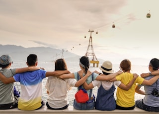 people holding shoulders sitting on wall