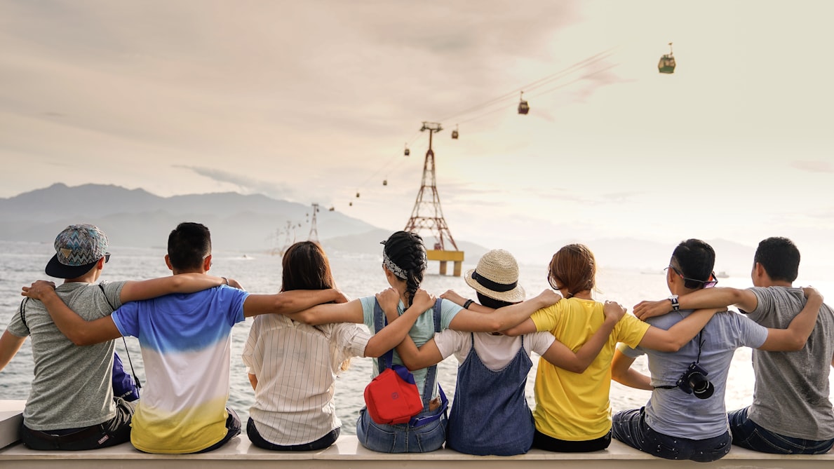 Group of people hugging, facing away from the camera looking out across the water