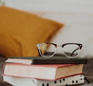 club master eyeglasses on pile of three books