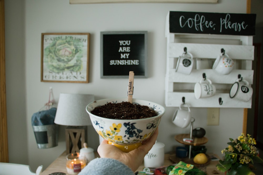 person holding white floral ceramic bowl