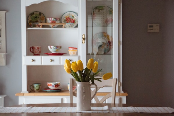 white kitchen shelf - yellow tulips in vase - ornate tea sets