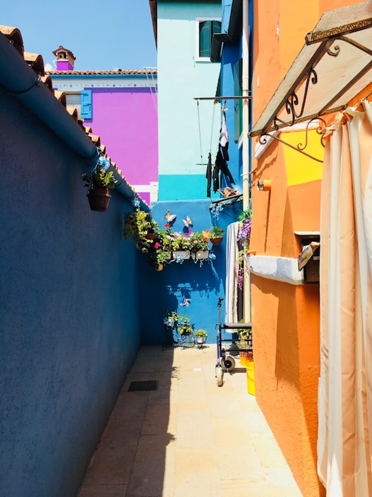 alley between blue and orange walls in Burano Italy