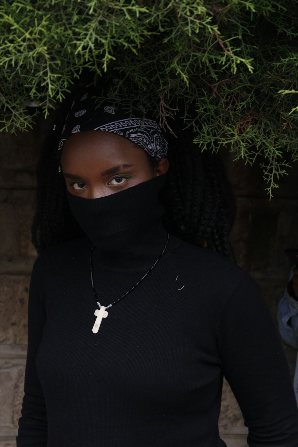 Femme en haut noir à col fermé debout devant le mur