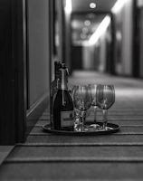 grayscale photo of wine glasses and bottle in tray