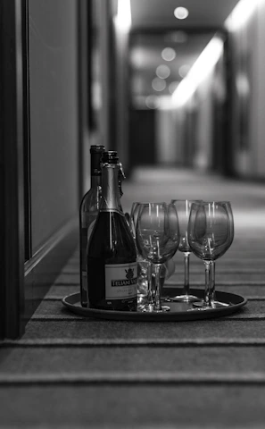grayscale photo of wine glasses and bottle in tray