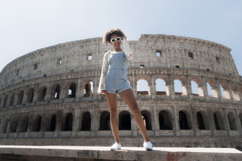 woman in blue romper shorts standing near The Coliseum