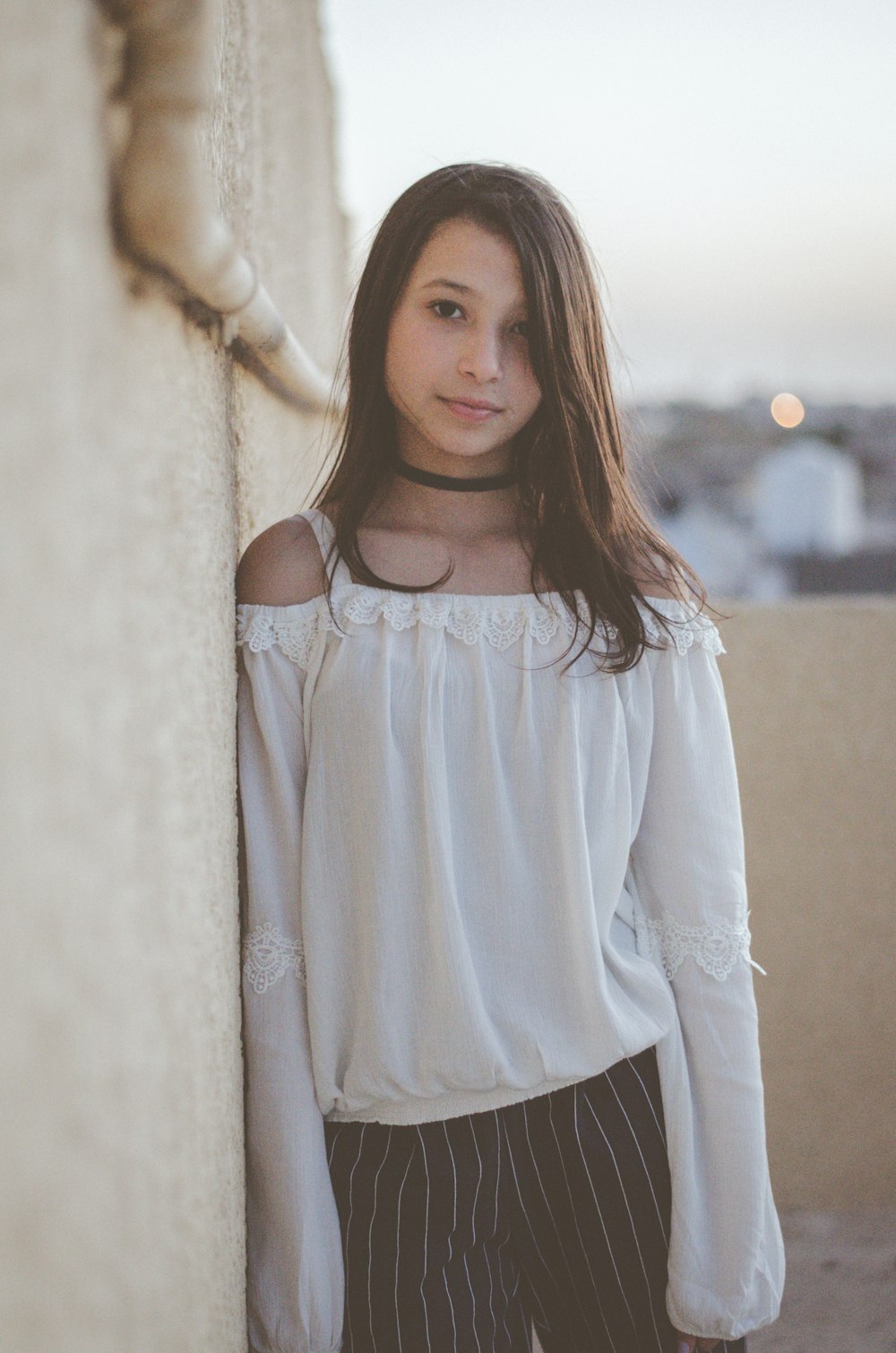 woman leaning on white wall