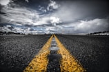 A freshly paved asphalt road stretching through a sunny landscape.