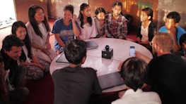 People discussing ideas around a table with digital devices and notes.