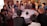 A diverse group of people engaged in a lively discussion around a table with laptops and notebooks.