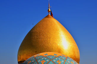A golden-hued close-up of the Dome of the Rock shining under a clear blue sky.