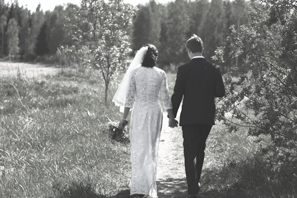 A bride and groom walking hand-in-hand through a lush garden, the bride’s dress flowing elegantly behind her.