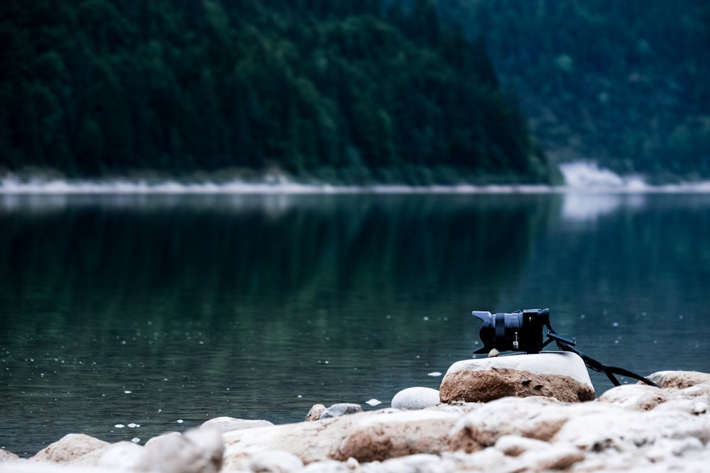 Cámara DSLR negra cerca del cuerpo de agua