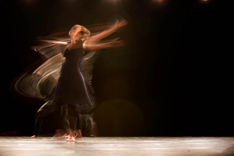 A contemporary dancer mid-leap on a dark stage