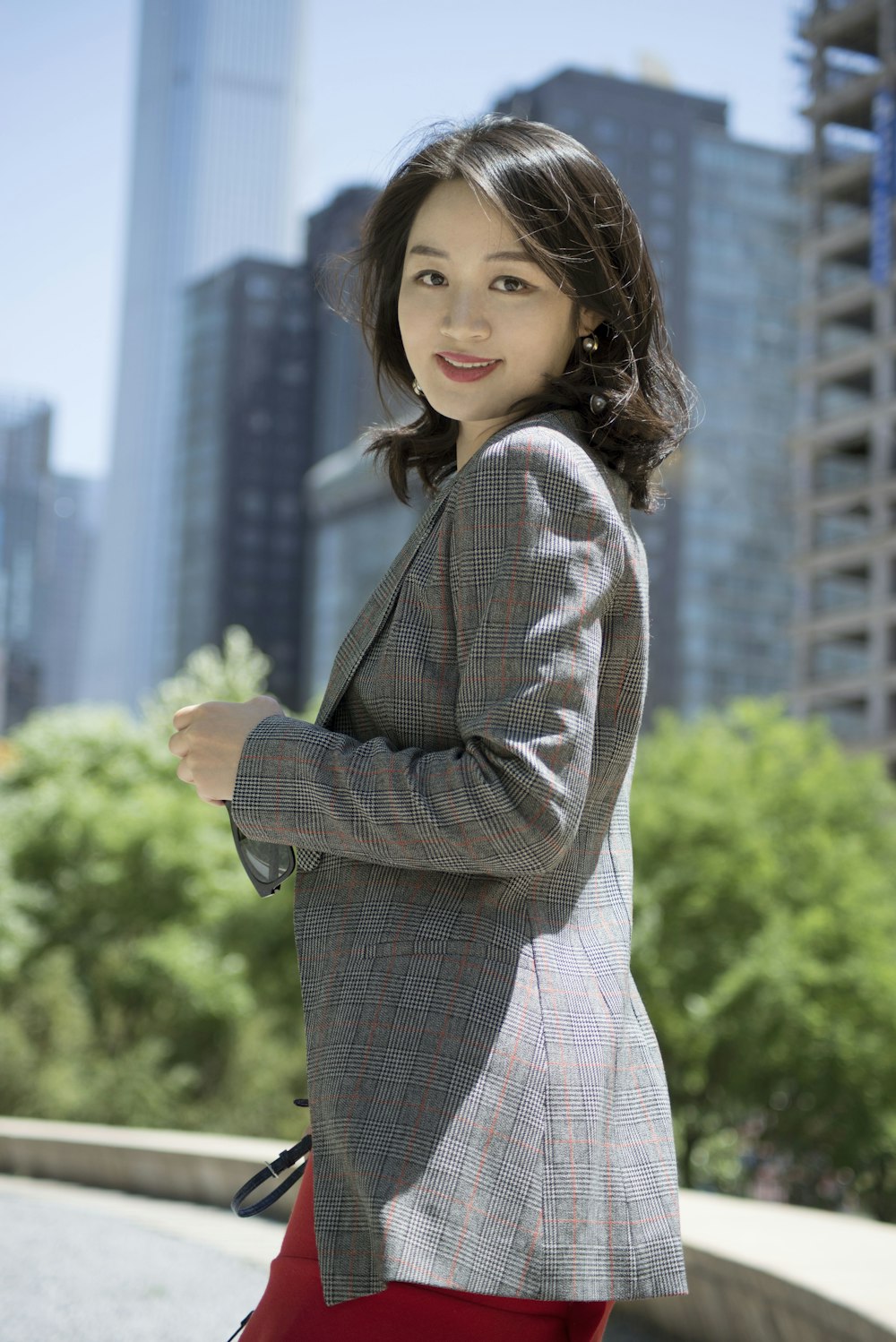 smiling woman wearing red, black, and gray plaid blazer