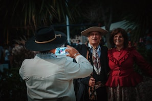 Group of northern Mexican ranchers wearing traditional hats, smiling and using smartphones