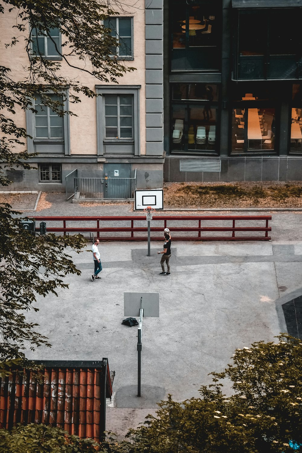 Zwei Männer spielen Basketball auf einem Basketballplatz in der Nähe von Gebäuden