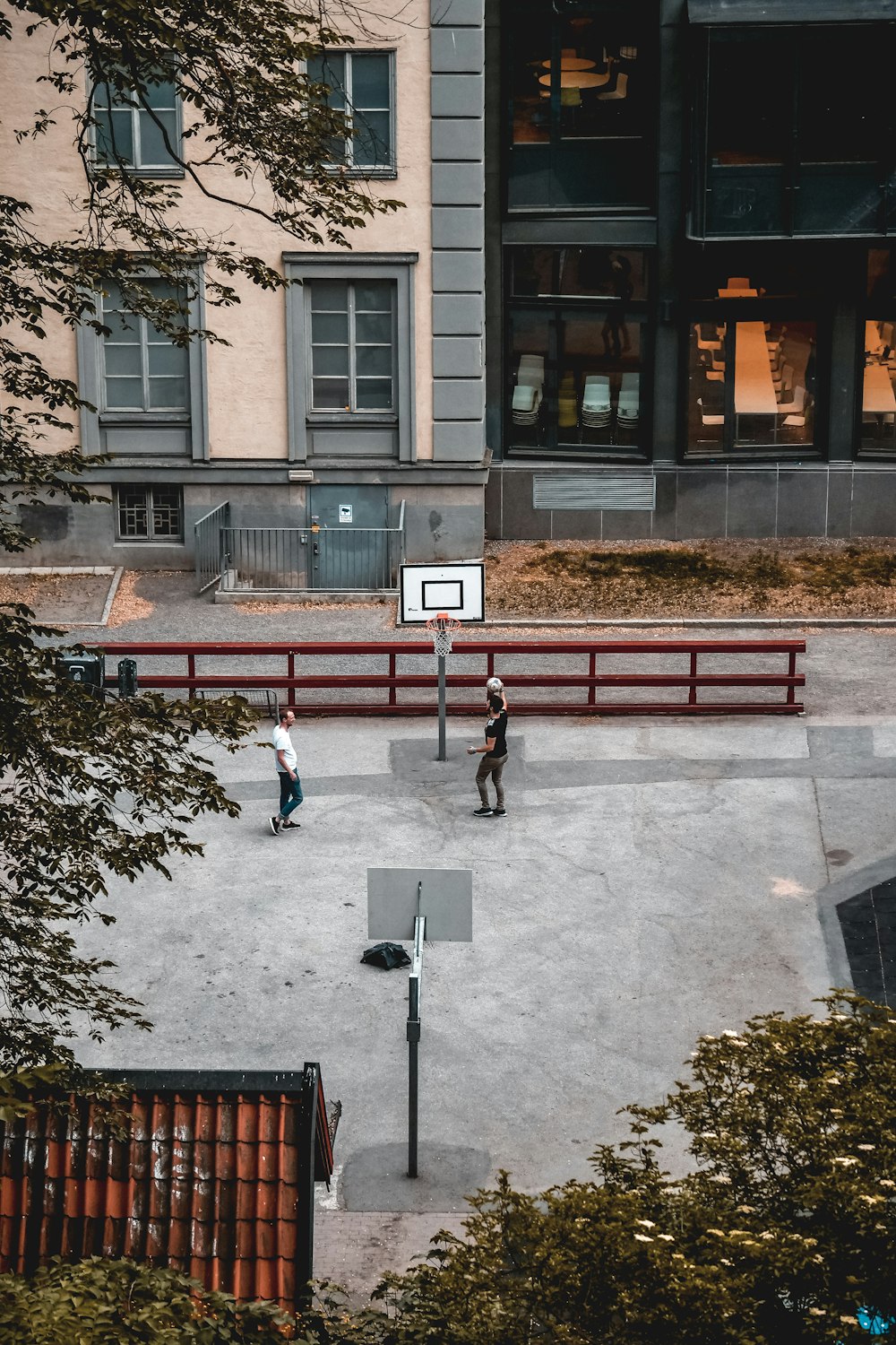 two men playing basketball on basketball court near buildings