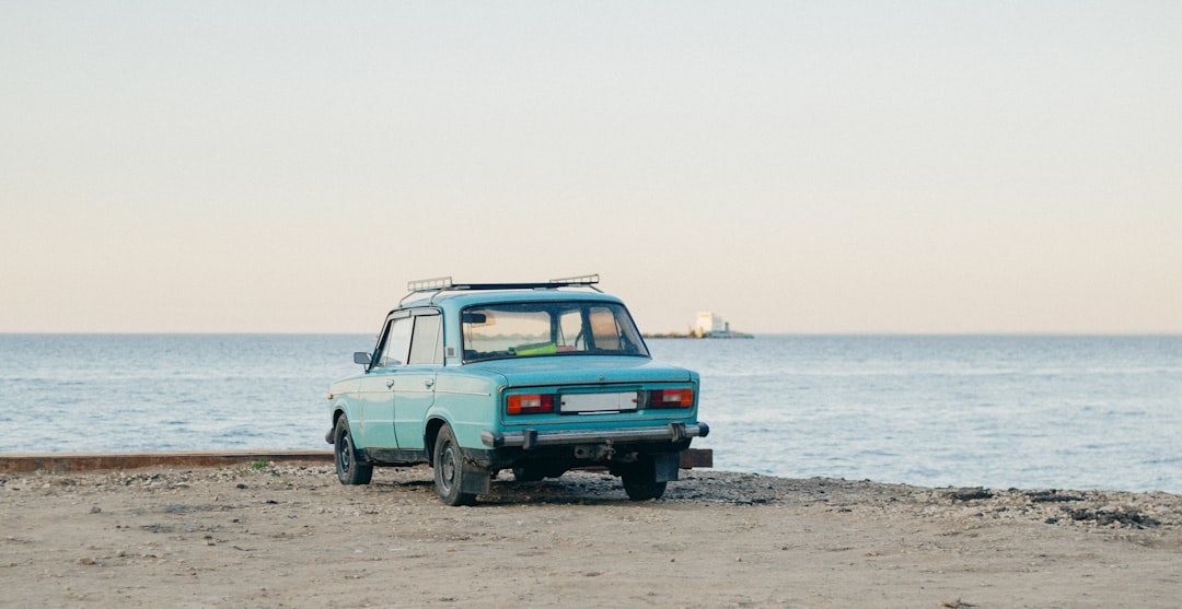 blue sedan near body of water