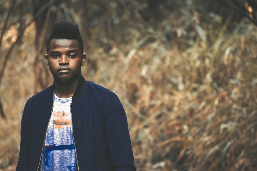 selective focus photography of man standing near brown grass