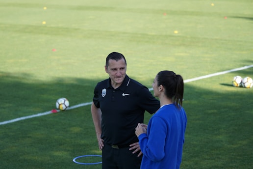 A dynamic sports agent discussing contracts with a young athlete on a soccer field.