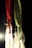 Two dreamcatchers hang against a dark background. The one on the left is red with white feathers and multicolored beads, while the one on the right is green with blue webbing and similar bead and feather decorations. A soft light highlights the textures and colors of the dreamcatchers.