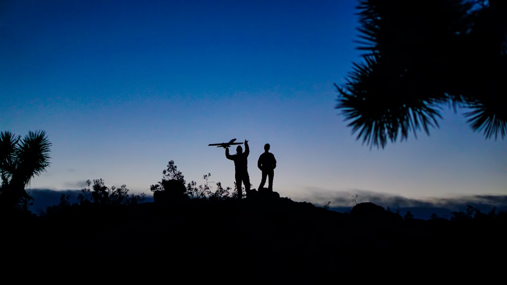 silhouette photo of man standing on boulder