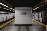A subway platform with tiled walls and a sign indicating the police transit bureau. The platform is almost empty, with a train visible on the right side. The tiles are white and the lighting gives the scene a slightly dim atmosphere.