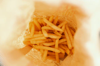A compact air fryer with crispy golden fries inside, steam rising gently.