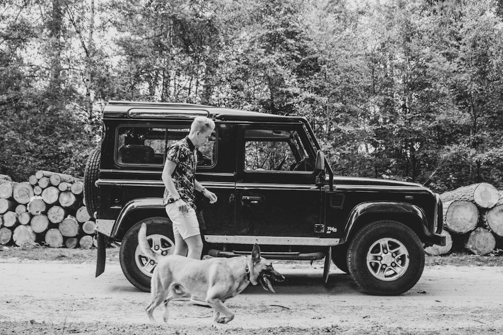 adult Belgian mallinois running beside man near car