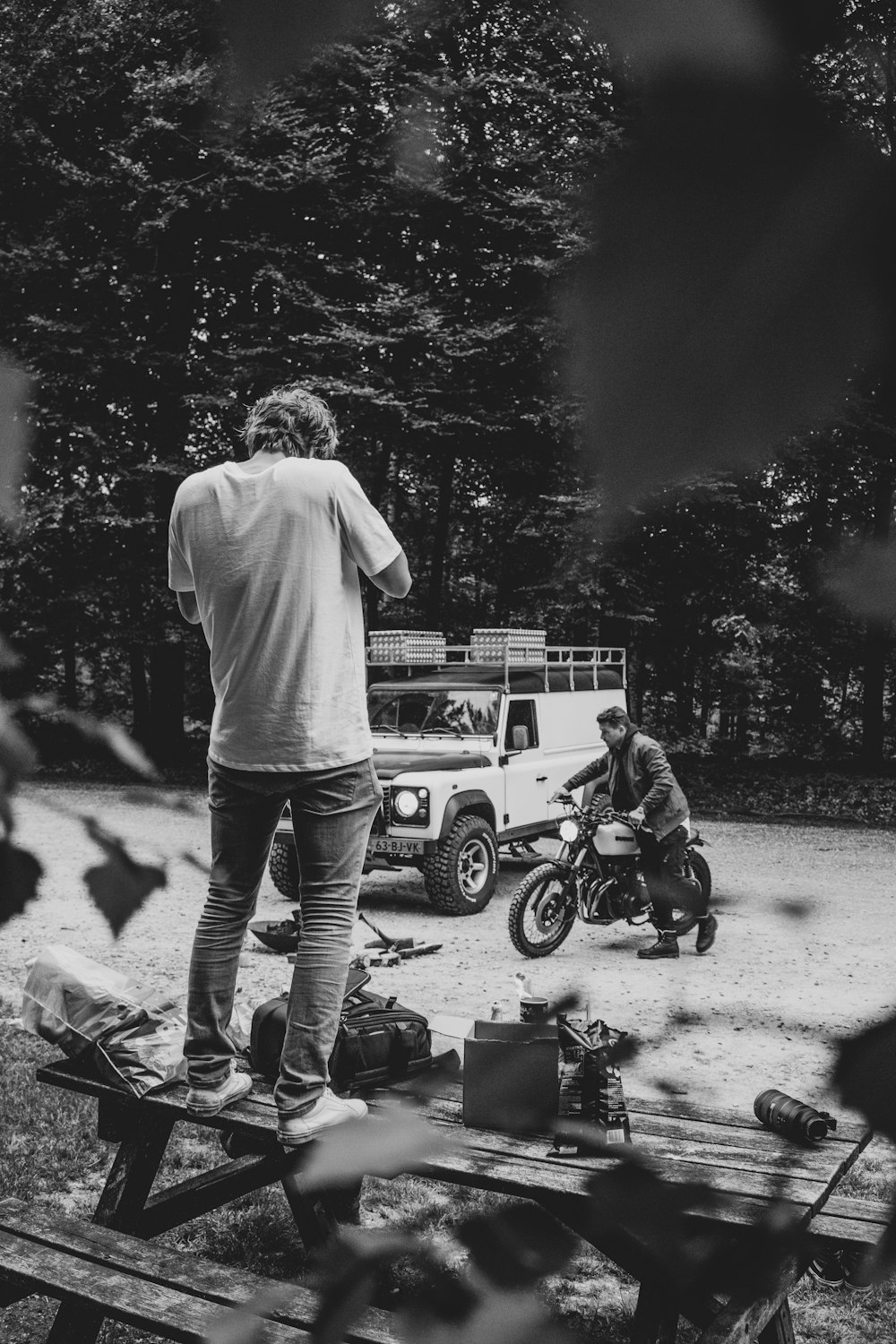 grayscale photography of man standing on picnic table