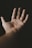 An open palm is centered against a dark background, with a small rainbow reflecting on the skin. The lighting creates a warm and intimate atmosphere, highlighting the textures and lines of the hand.