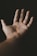 An open palm is centered against a dark background, with a small rainbow reflecting on the skin. The lighting creates a warm and intimate atmosphere, highlighting the textures and lines of the hand.