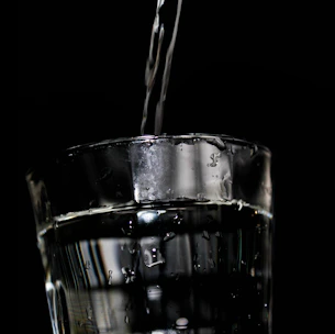 Close-up of crystal-clear water pouring into a glass under natural light.