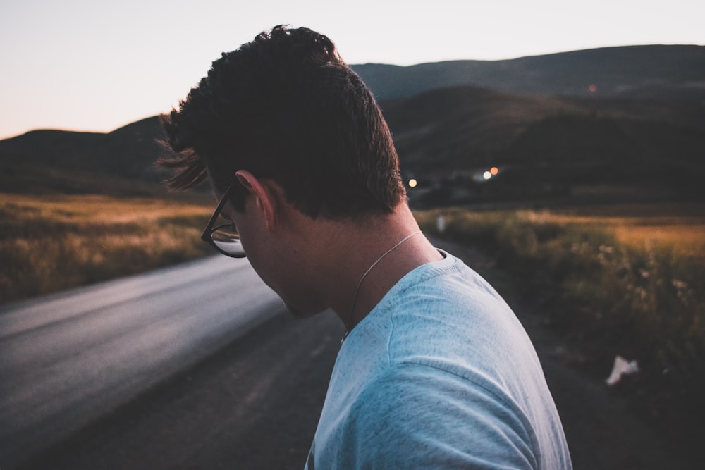 Photographie à mise au point peu profonde d’un homme sur la route regardant le sol